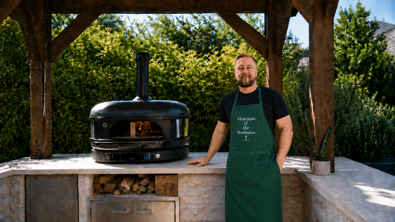 Jeff from Star Ranch Kitchen standing in front of a wood-fired Gozney oven in his backyard kitchen.